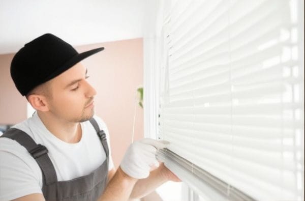 A man is inspecting the blinds before taking them down