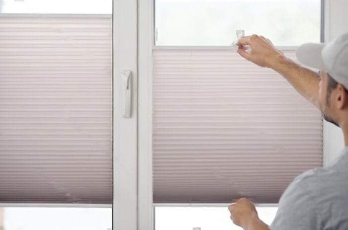 showing How To Pull Down Blinds Without Strings and their working by a man