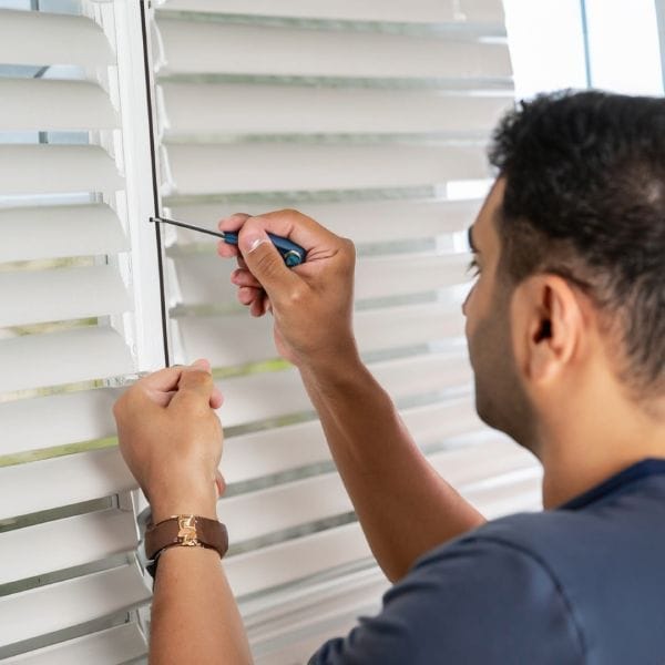 a man is using screwdriver to replace Levolor blinds