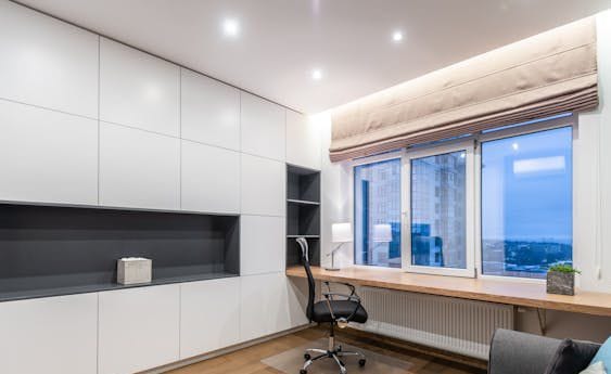 Motorized blinds in a room with the office setup offering a beautiful night view.
