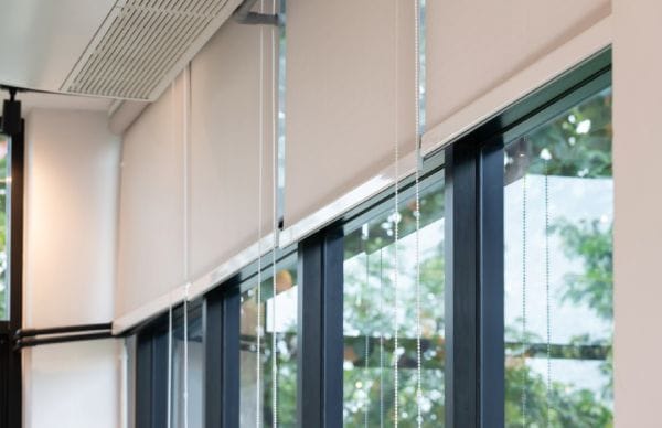 White roller blinds for glass windows followed by black window frames.